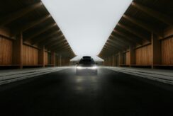 A car approaches through a wooden structure.